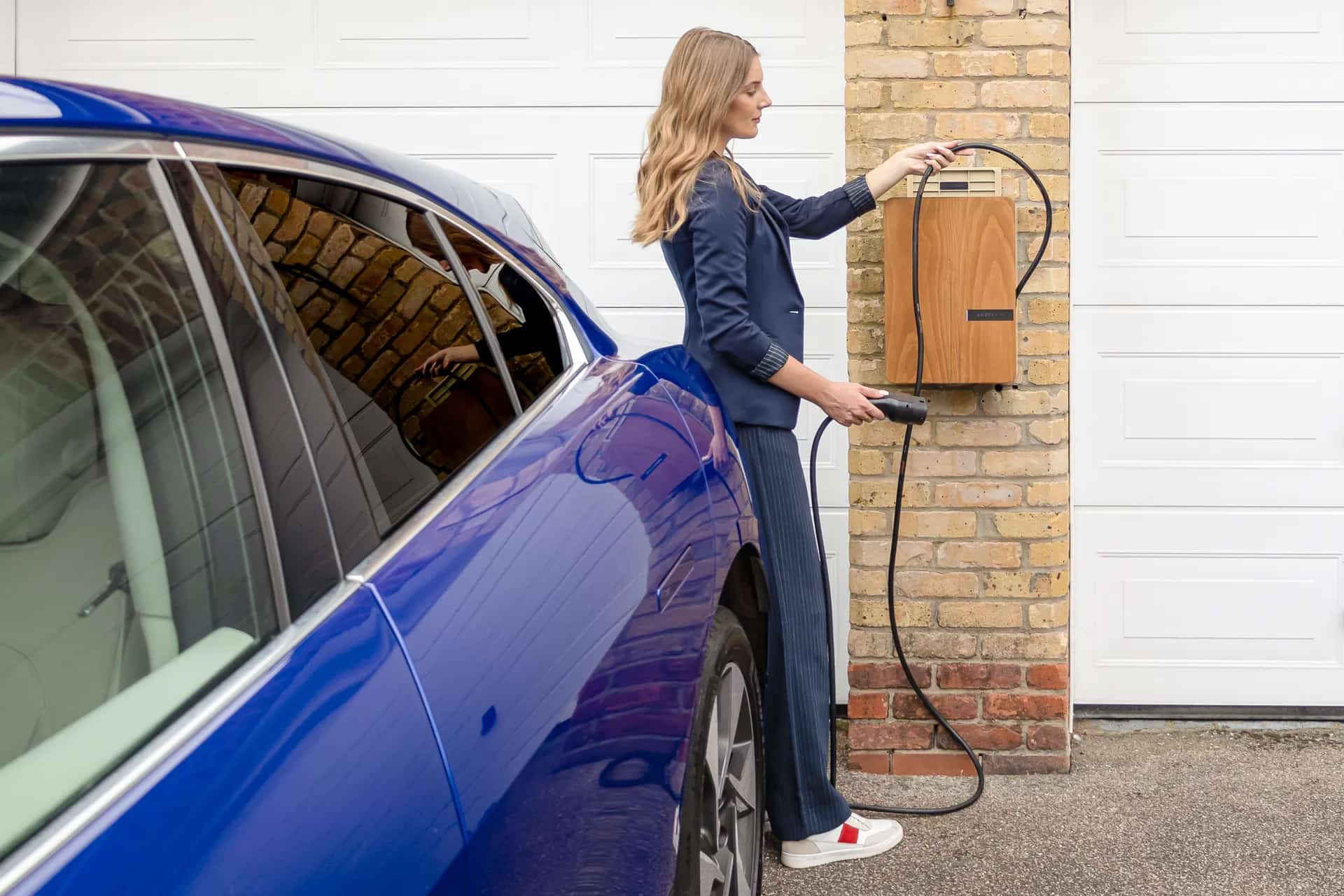 Nő tölti elektromos autóját otthon, nyugodt pillanatban